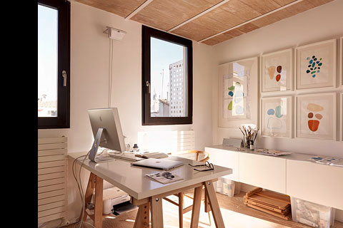 working room, table with monitor screen and computer, glass framed abstract paintings on the wall